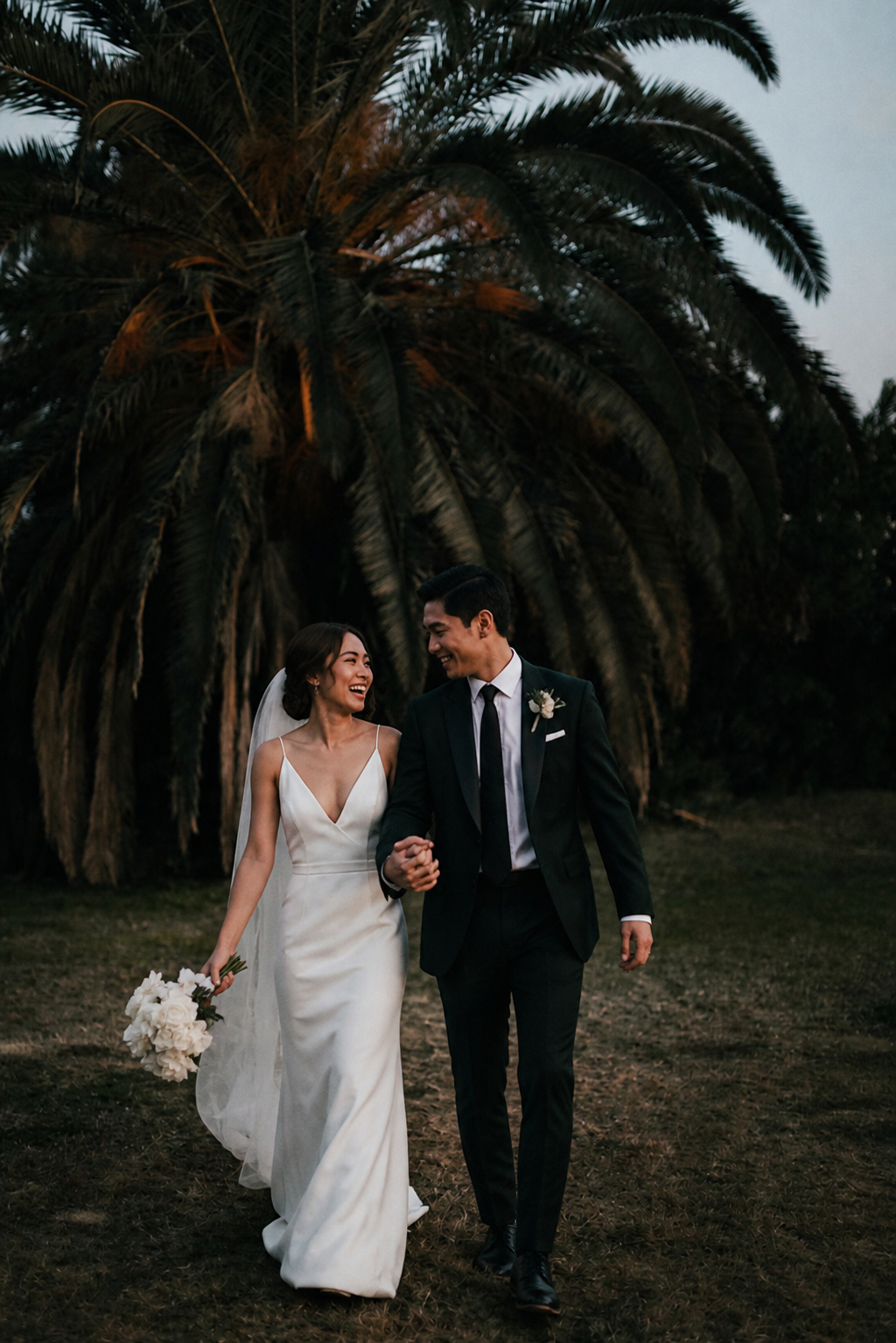 Couple walking through a field at sunset on their wedding day